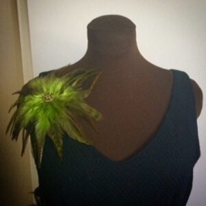 Dress with a large green feather accessory on the shoulder.