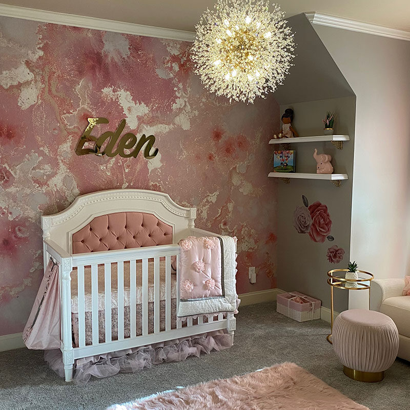 Cozy nursery with floral wallpaper and soft pink accents.