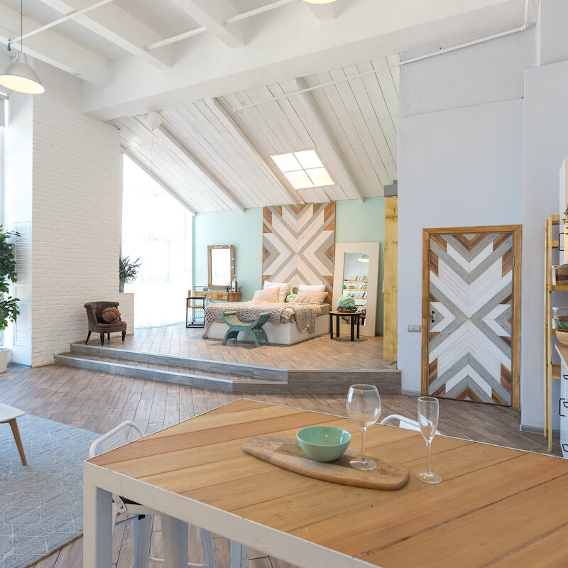 Modern dining area with wooden table and geometric decor in a bright, airy room.