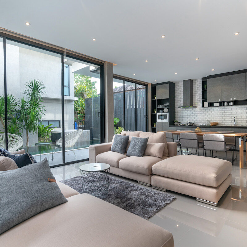 Modern living room with large glass doors and beige sectional sofa.