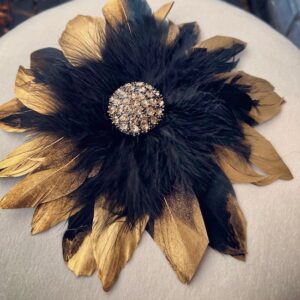 Elegant black and gold feathered flower brooch with a jeweled center.