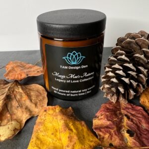 A candle jar surrounded by autumn leaves and pinecones.