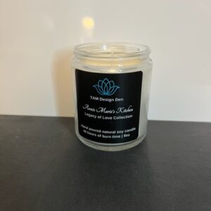 A lit scented candle in a clear glass jar with a black label.